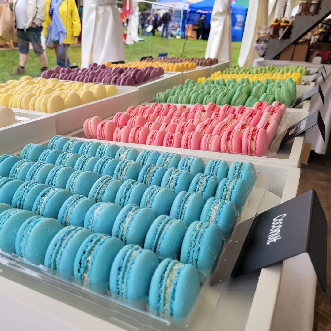 brightly coloured macaroons on display at a market stand.