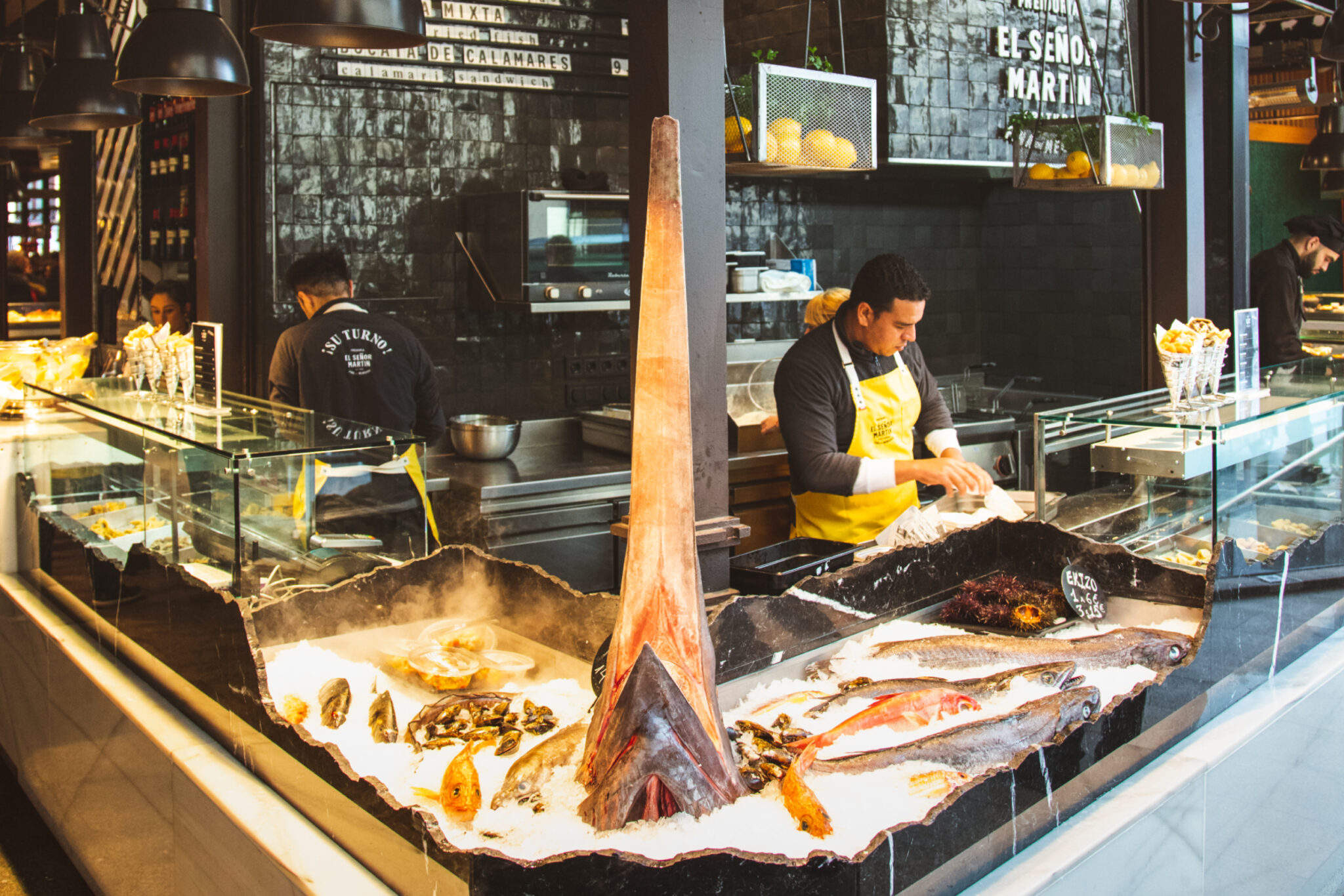 Man working behind the counter at a seafood and food market stall.