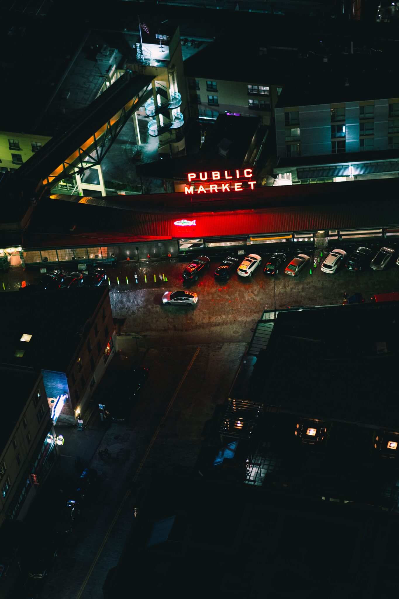 nighttime photo of the outside of Public Market in Seattle with the name lit up in red.