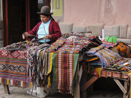 Woman selling colourful rugs, carpets and scarves at a market in South America.