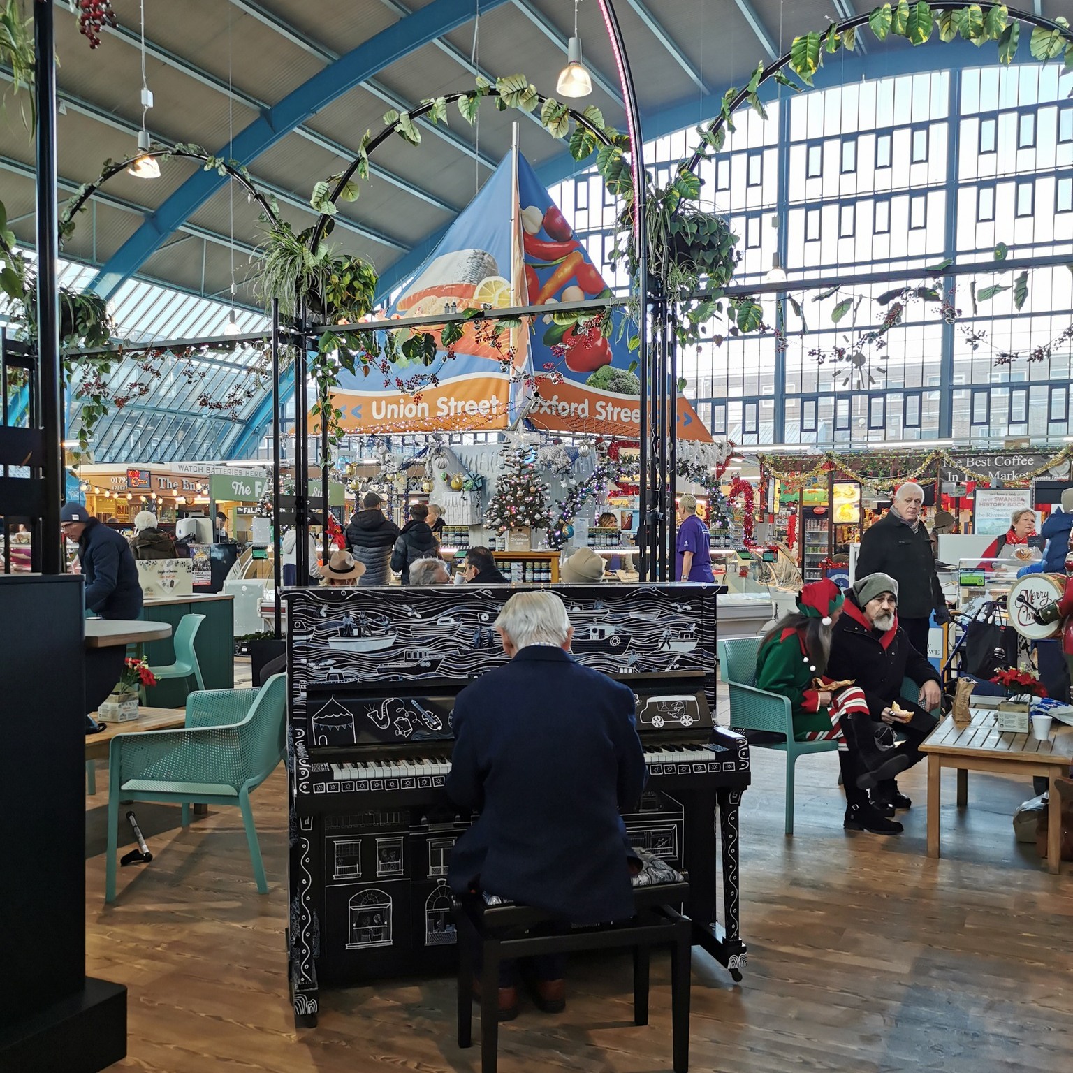 A man playing the piano inside the Swansea Market.