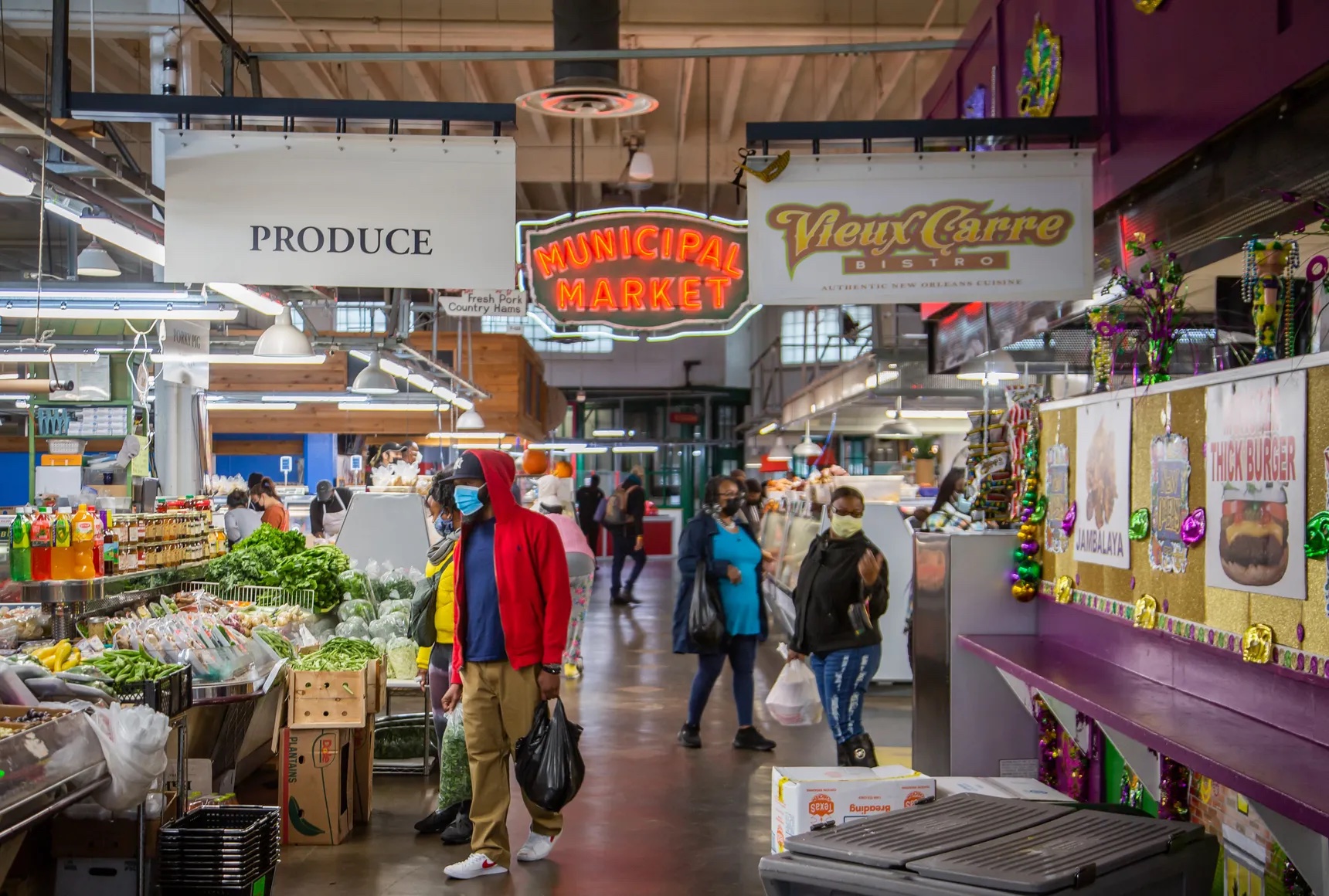 People wearing masks walking down aisles at an indoor market.