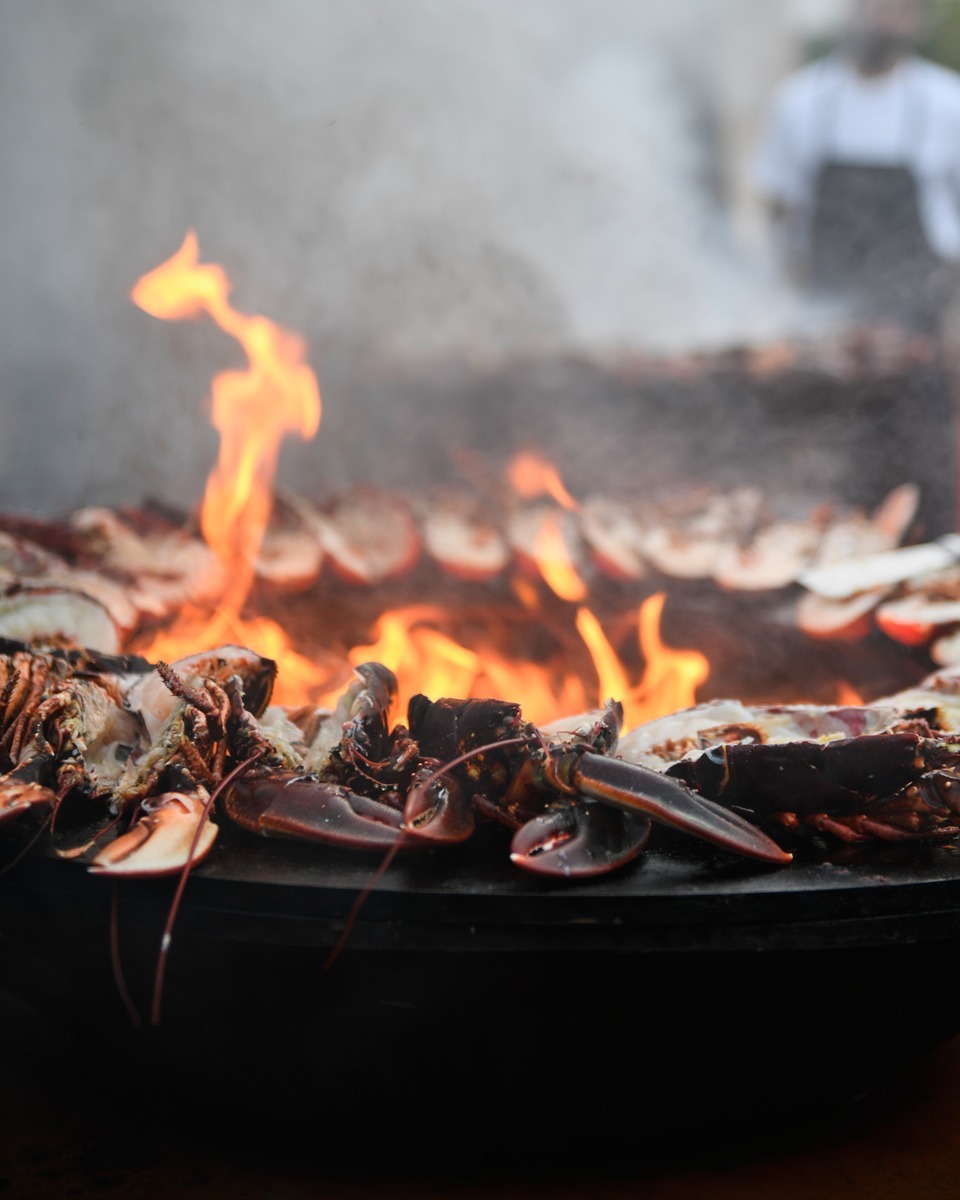 Lobster sitting around the rim of a fire pit.