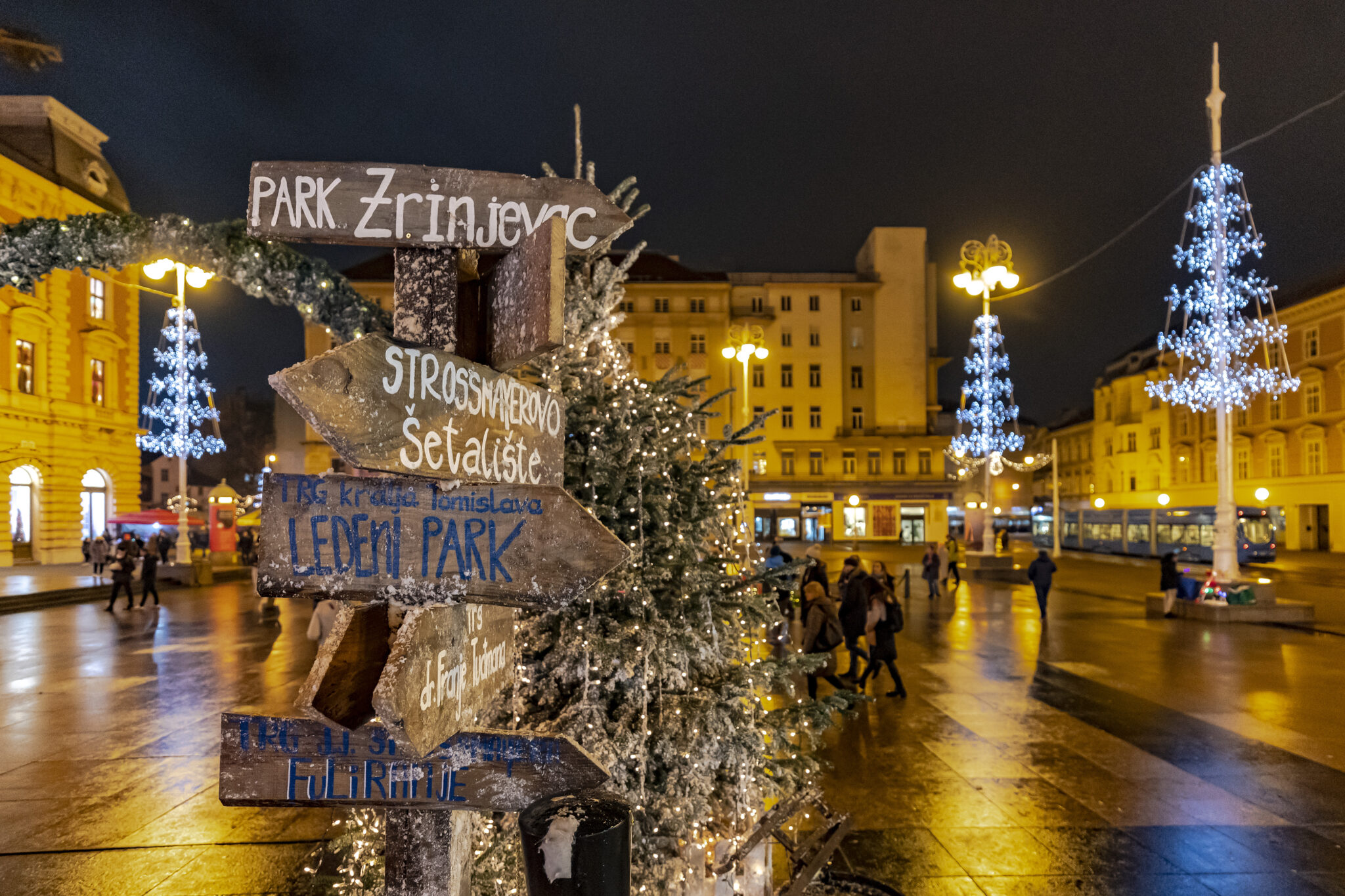 Sign posts stating stalls in different directions at the Advent in Zagreb market, held in a town square.