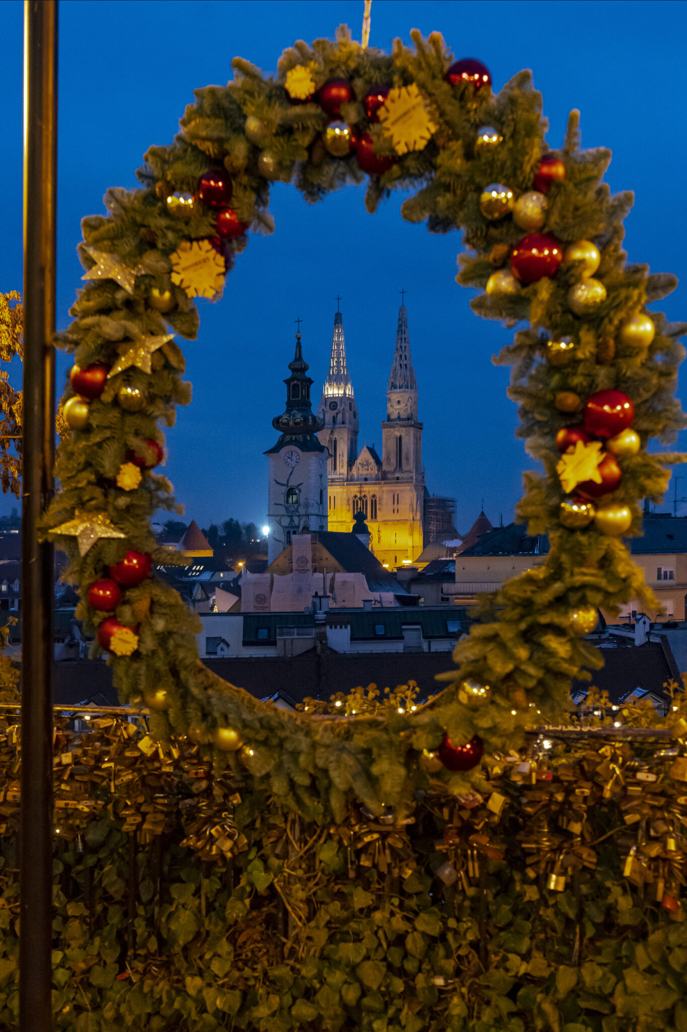 View of the city of Zagreb in the background, looking through a christmas wreath, hanging at a stall at the Advent in Zagreb market.